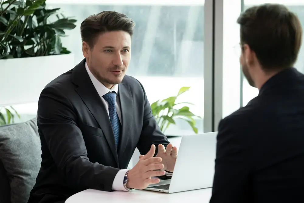 Candidat en costume échangeant avec un recruteur lors d'un entretien de recrutement pour la fonction publique.