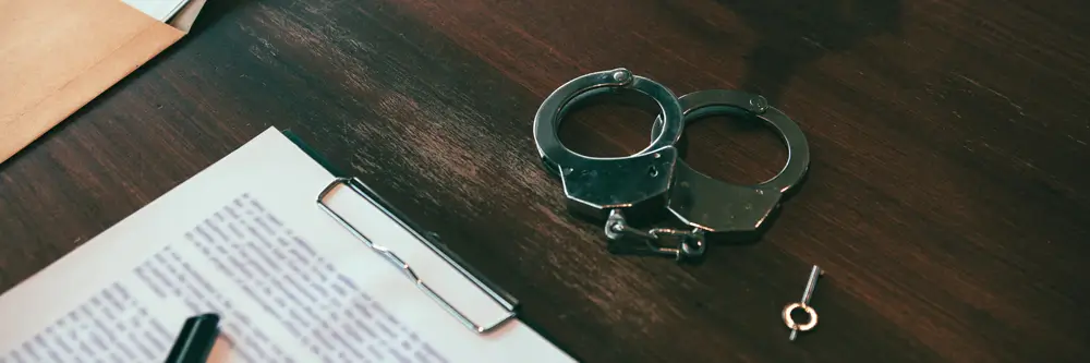 Menottes posées sur un bureau à côté de documents officiels, illustrant le poids des antécédents judiciaires.