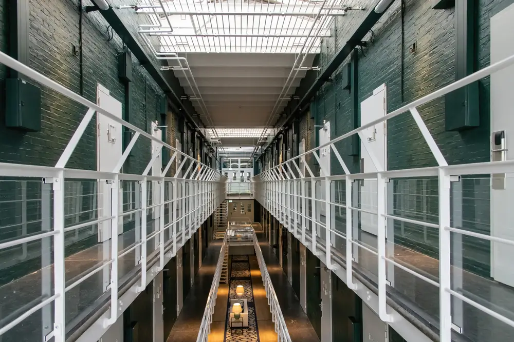 Couloir d'une prison belge avec cellules et garde-corps blancs, cadre de travail d'un agent pénitentiaire surveillant.