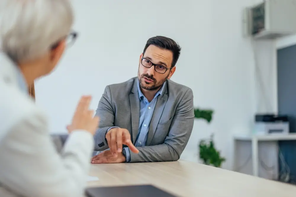 Un candidat échangeant avec une recruteuse lors d'un entretien d'embauche professionnel au sein d'un bureau.
