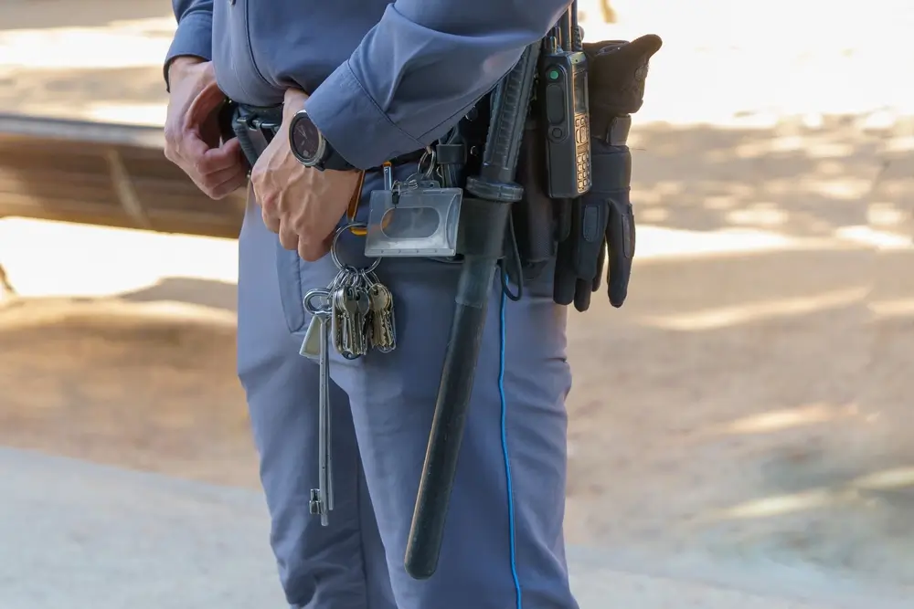 Trousseau de clés et équipement de sécurité à la ceinture d'un agent pénitentiaire en uniforme.