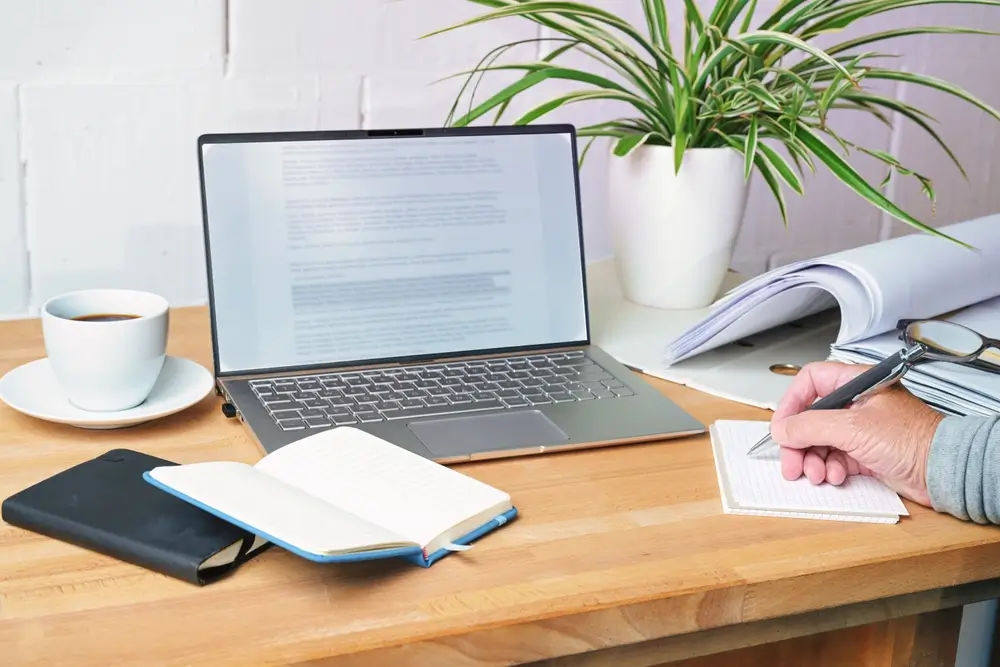 Prise de notes devant un ordinateur et des dossiers ouverts pour se préparer activement aux épreuves de sélection.