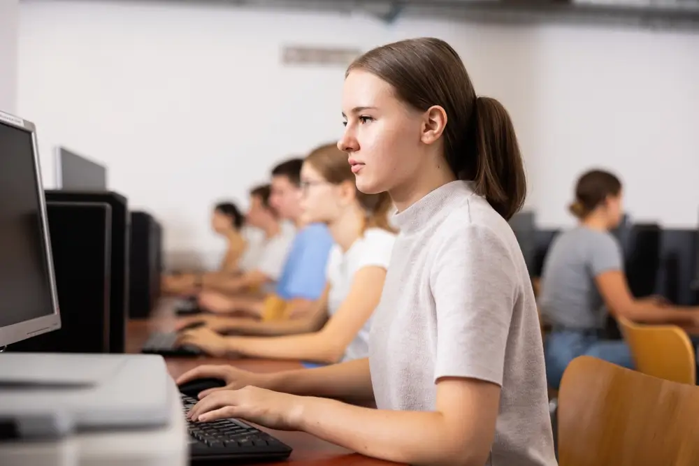 Candidate concentrée devant son écran et clavier d'ordinateur lors d'une épreuve informatisée de sélection.