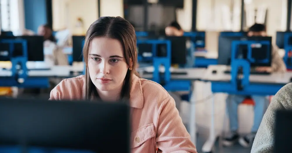 Une jeune femme concentrée passant un test sur ordinateur dans un centre de sélection.