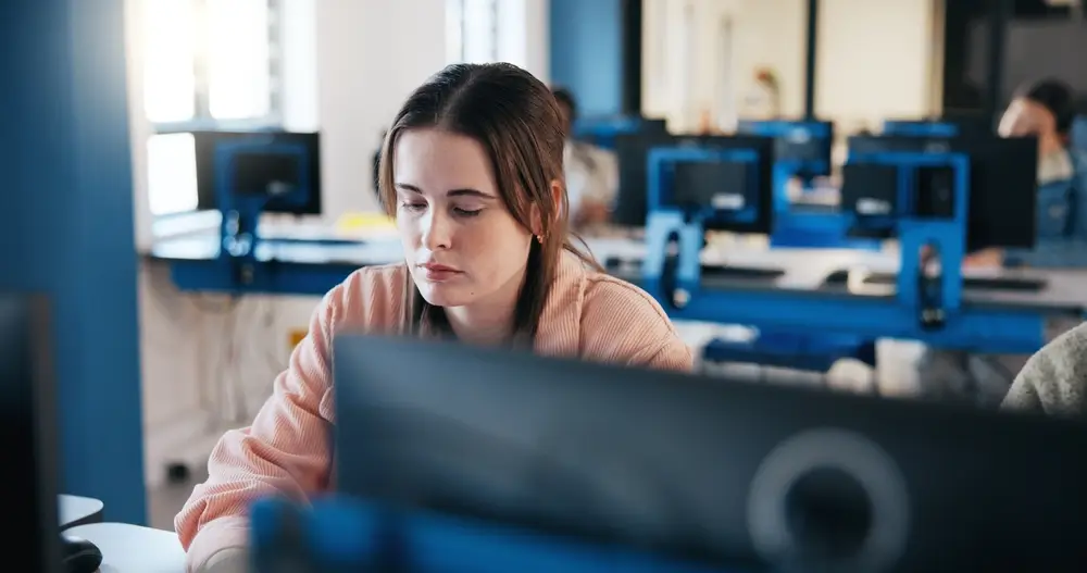 Candidate concentrée devant son ordinateur lors d'un test de sélection informatique dans un centre d'examen.