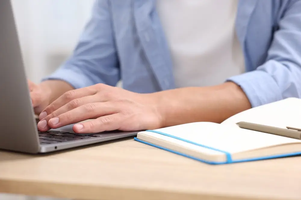 Candidat passant un test de recrutement en ligne ou un entretien sur son ordinateur avec un carnet de notes.