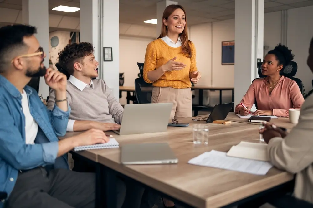 Professionnels en réunion de travail collaborative illustrant une mise en situation d'équipe dans un bureau.