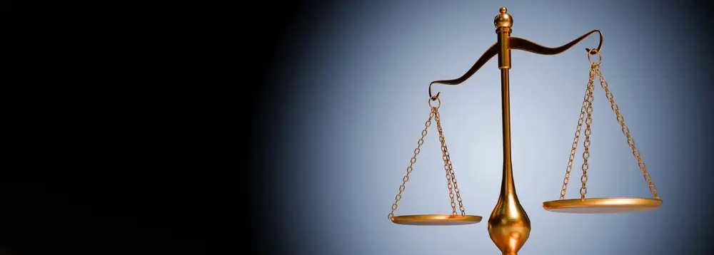 Balance de la justice dorée sur fond sombre, symbole de l'institution et du cadre légal pénitentiaire.