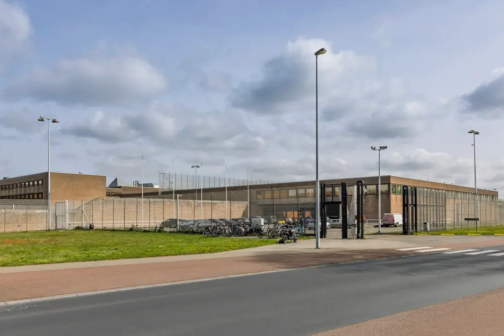 Bâtiment de prison avec mur d'enceinte et clôtures de sécurité, lieu d'exercice d'un assistant de surveillance.