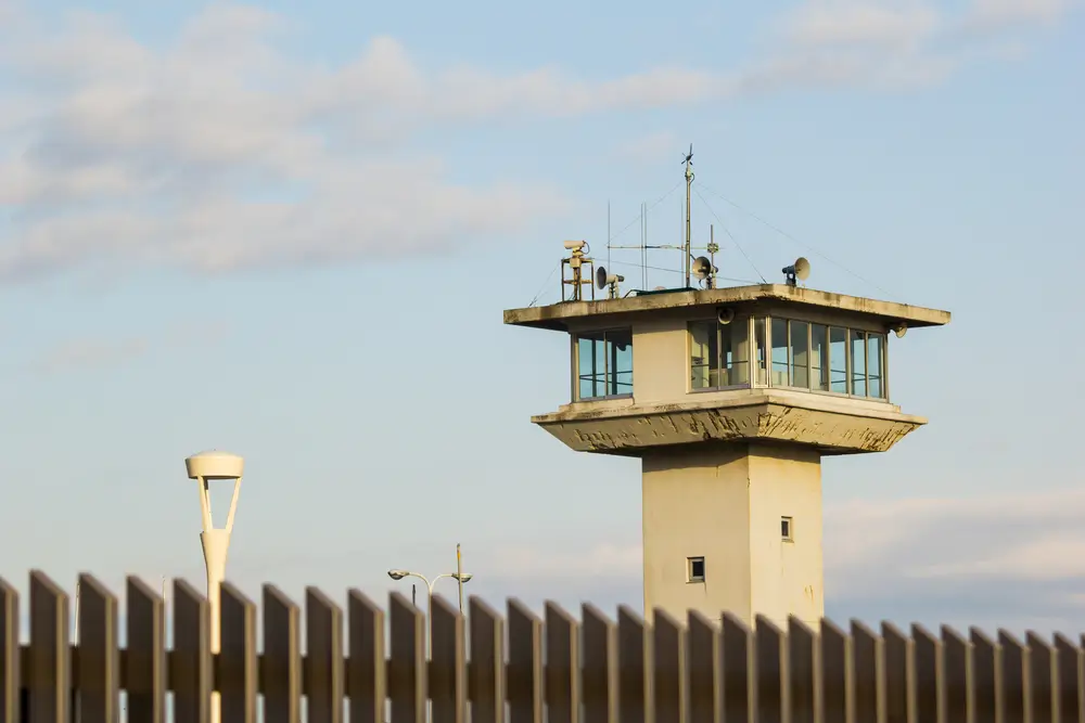 Mirador de surveillance d'une prison avec caméras et haut-parleurs derrière un mur d'enceinte.