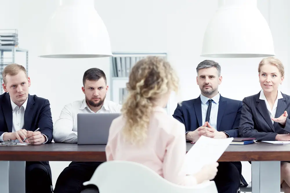 Candidate de dos face à un jury de recrutement composé de quatre personnes lors d'un entretien d'embauche.